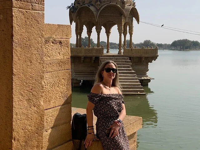 Frau sitzt an einem See mit einem Steinpavillon im Hintergrund