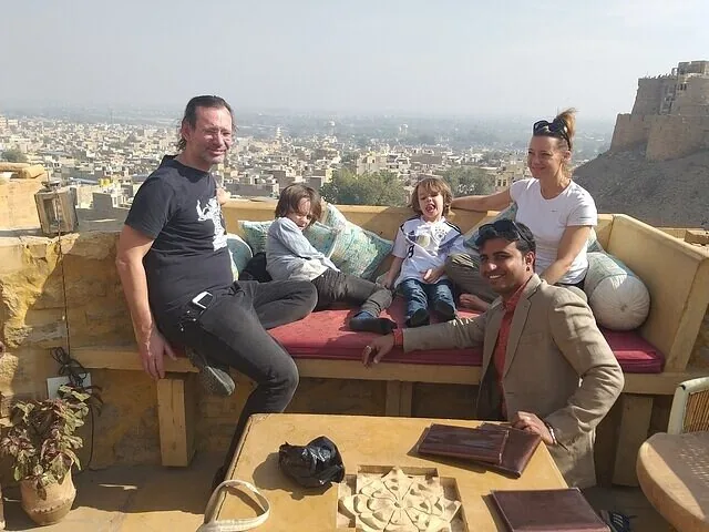 Familie und Guide entspannen auf einer Dachterrasse mit Blick auf die Stadt Jaisalmer